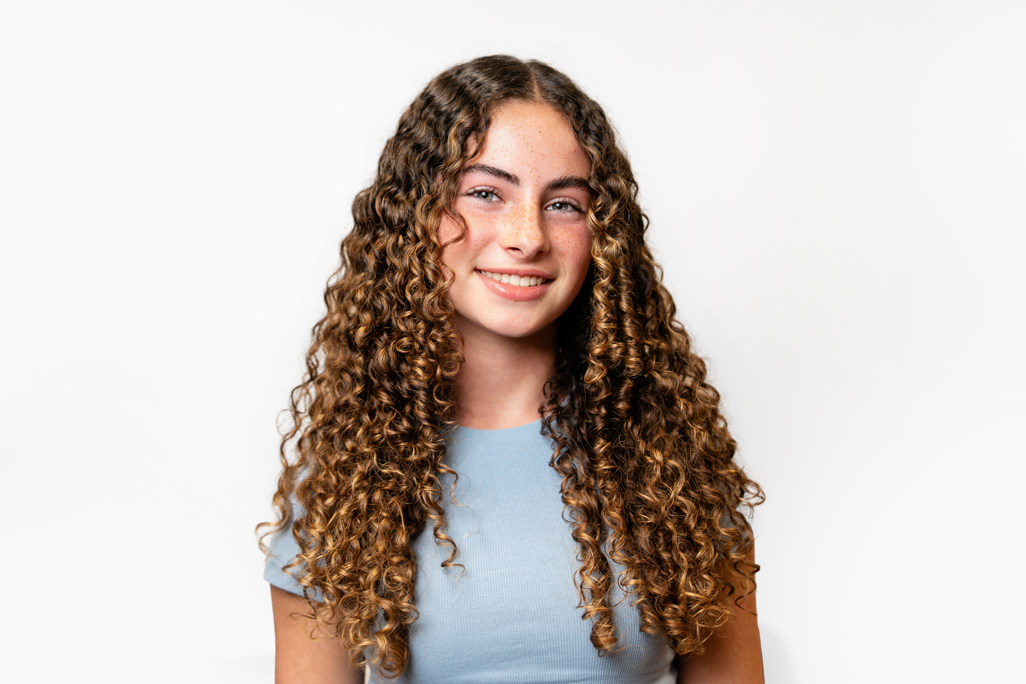 Smiling teen patient with curly hair showcasing healthy smile at Maui Orthodontics.