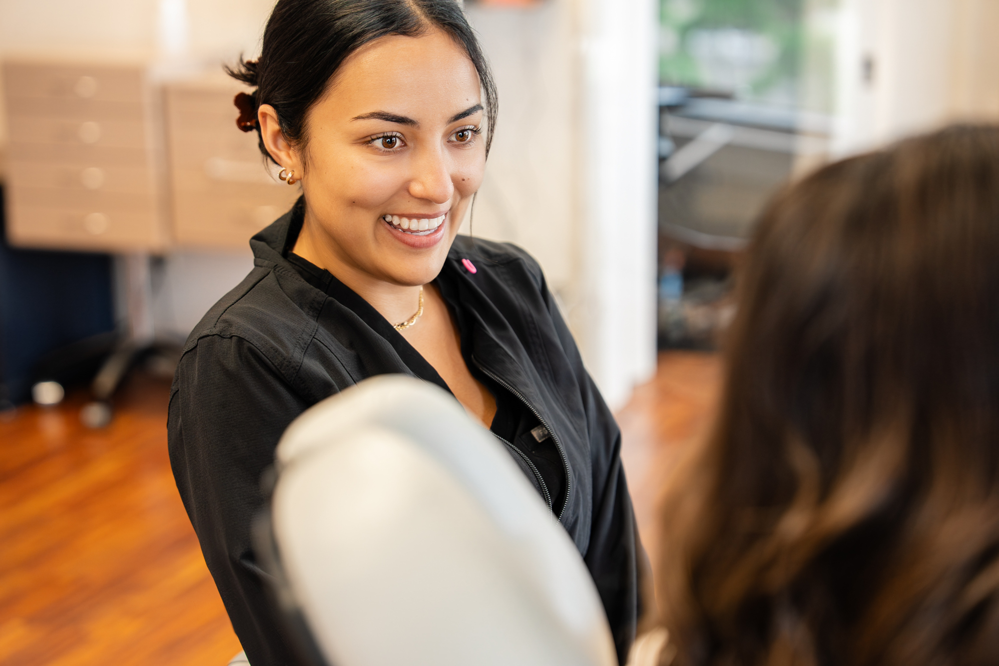 Smiling Maui Orthodontics team member in black scrubs greeting a patient at the practice of Dr. Paul and Dr. Aurelia Bonham
